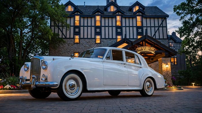 White 1959 Bentley S in front of a country inn entrance at blue hour