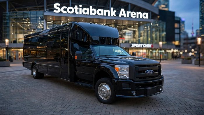 Black Ford F-550 party bus on a paved plaza outside a downtown Toronto arena in the evening