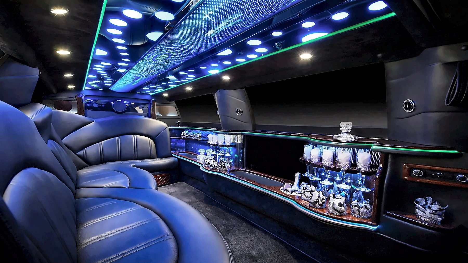 Interior of the Lincoln MKT Stretch with leather seating, a bar with glassware and blue cabin lighting