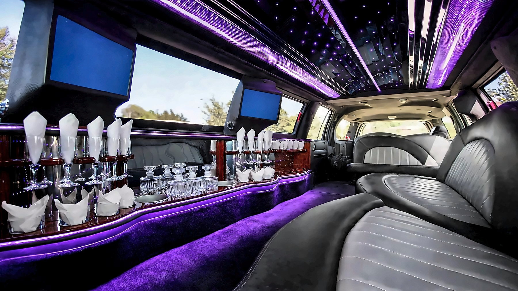 Interior of the Lincoln Navigator Stretch with leather seating, screens, a bar and purple cabin lighting
