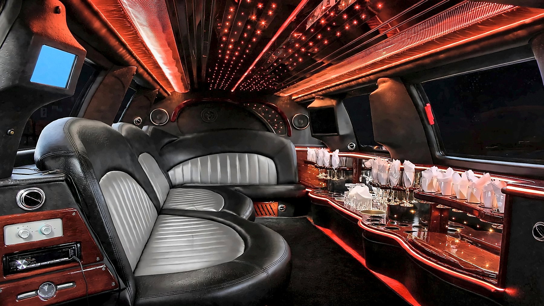 Interior of the Lincoln Navigator Stretch with wraparound leather seating, a bar and red cabin lighting