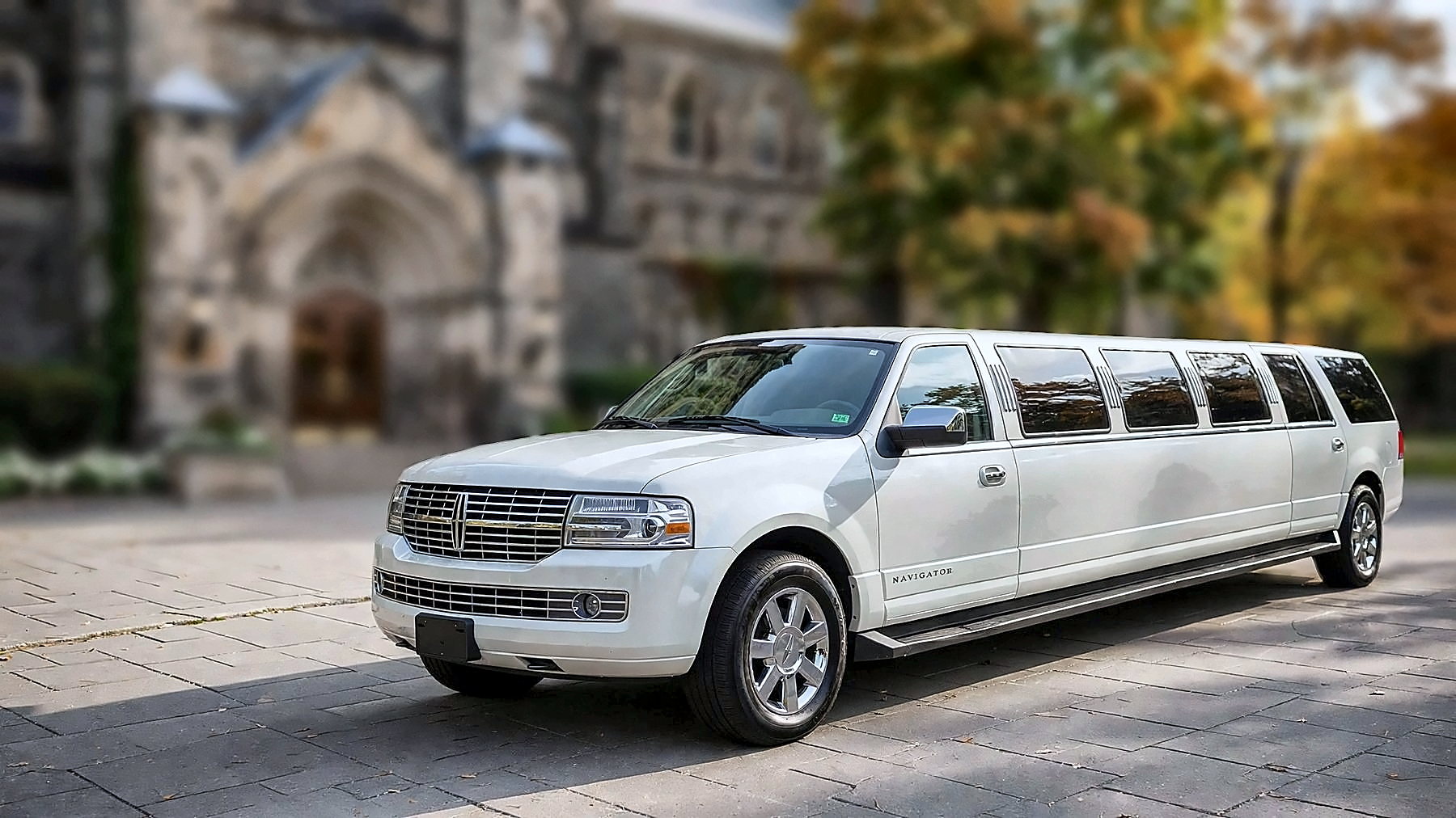 White Lincoln Navigator Stretch, 14 passengers, on a university campus in autumn