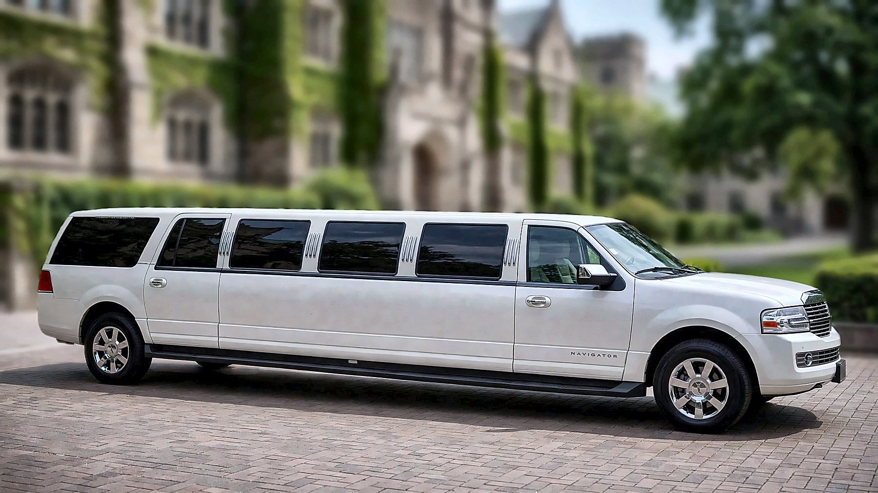 The white Lincoln Navigator Stretch in side profile on a university campus