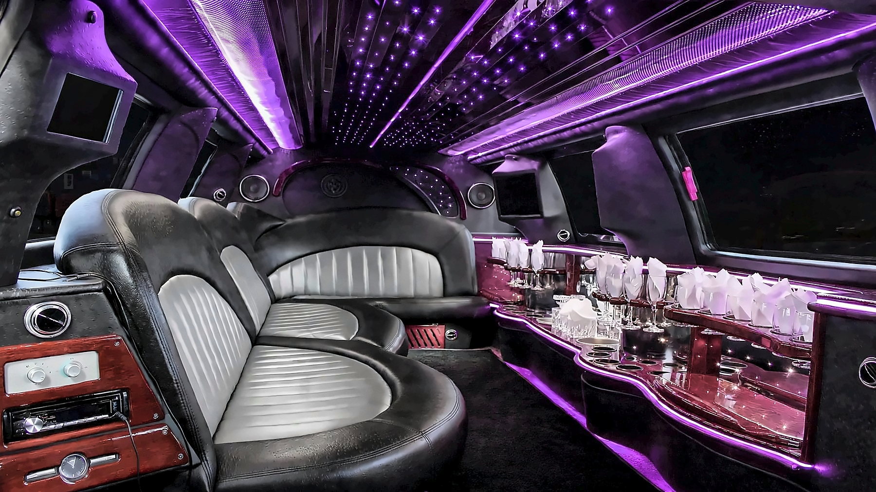Interior of the Lincoln Navigator Stretch with wraparound leather seating, a bar and purple cabin lighting