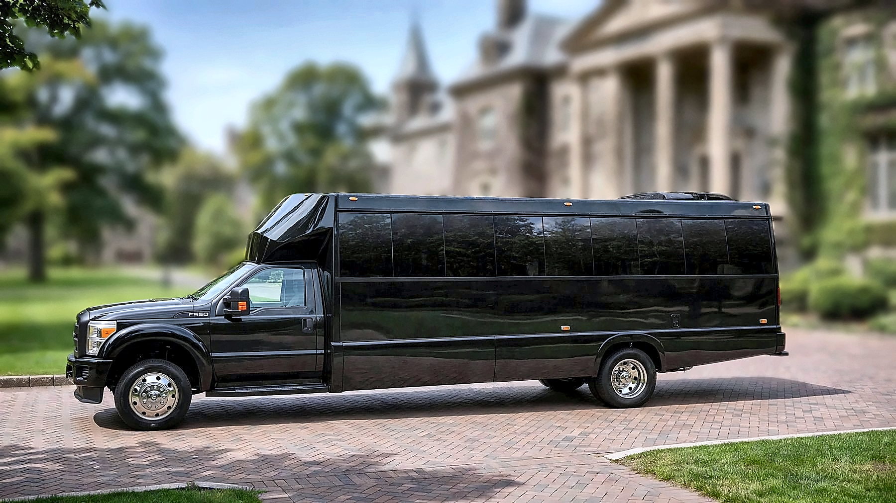 The black Ford F-550 Party Bus in side profile on a university campus