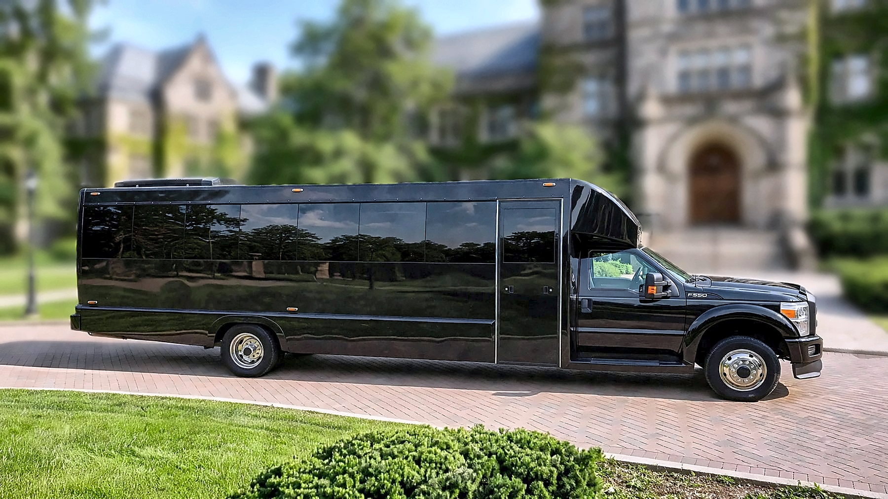 The black Ford F-550 Party Bus in full side profile on a university campus