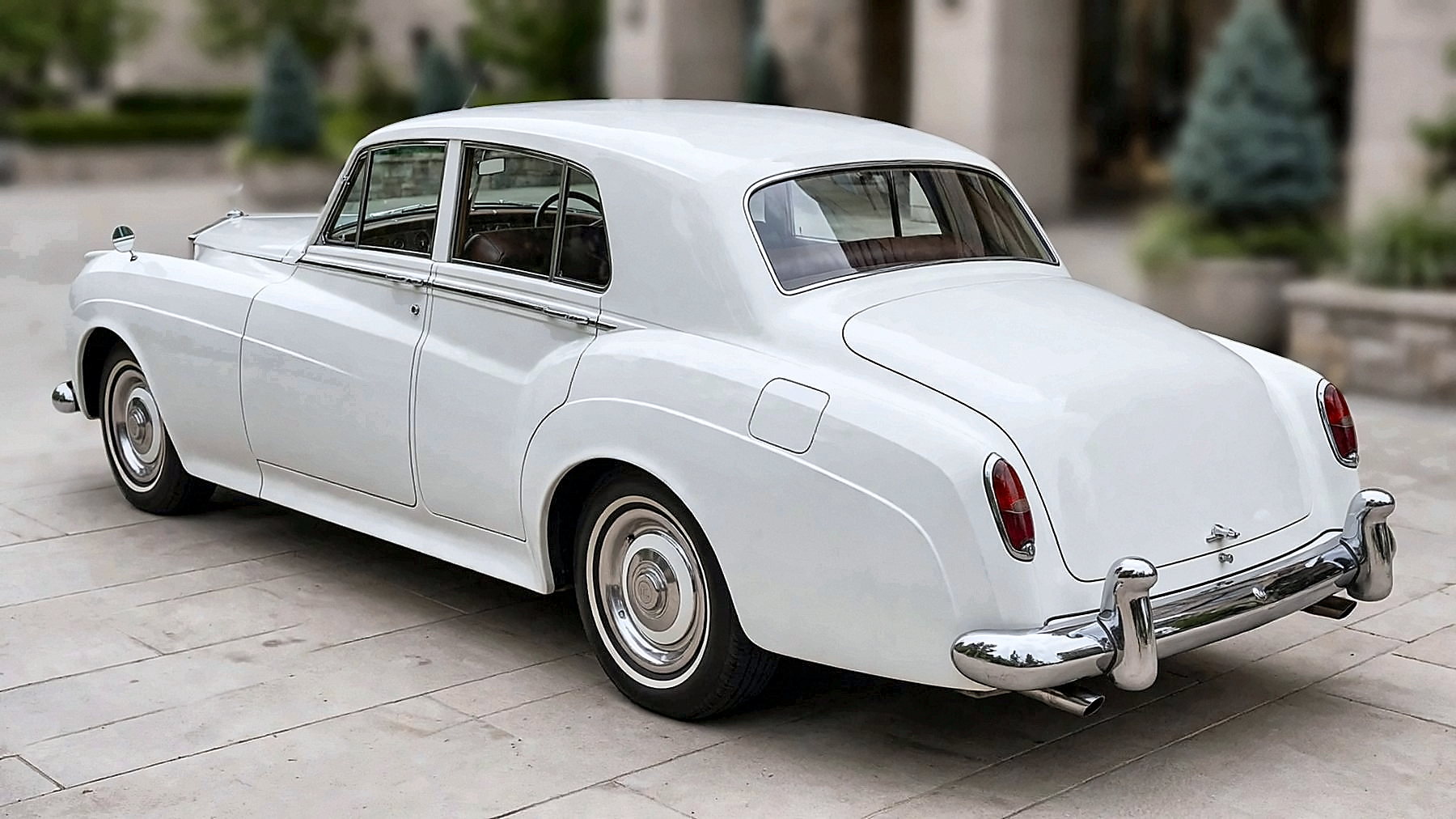The white 1959 Rolls-Royce from the rear, at an estate entrance