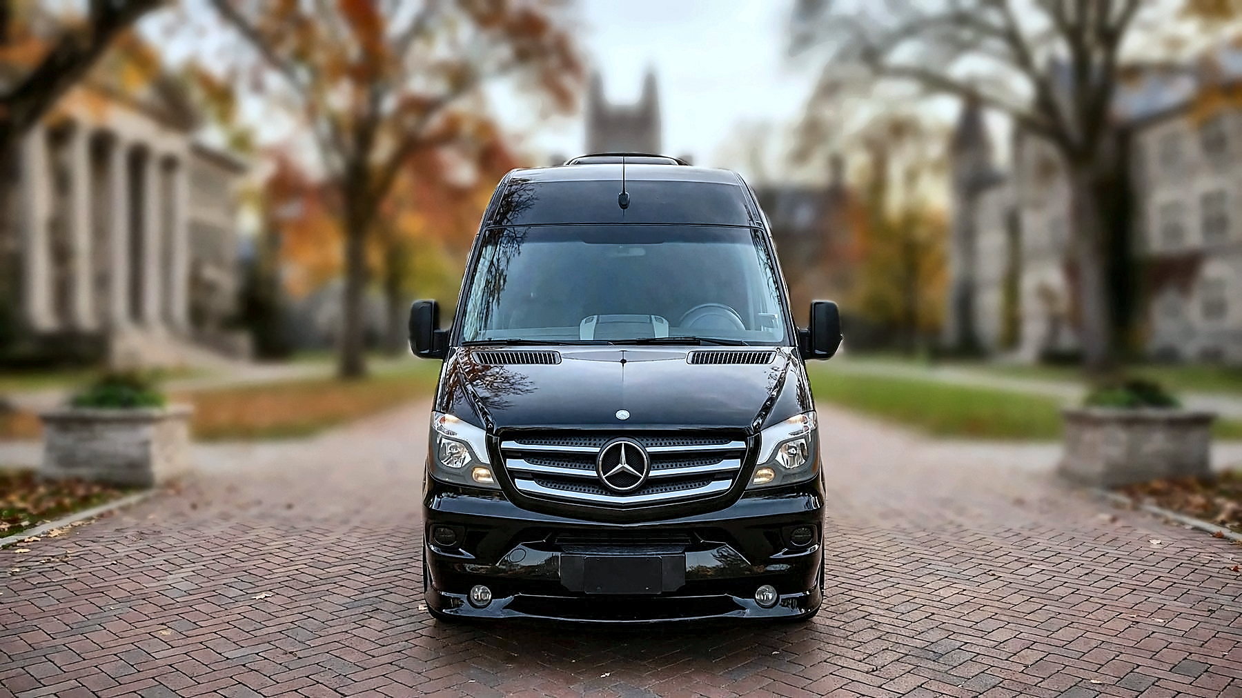 The black Mercedes-Benz Sprinter from the front on a university campus in autumn