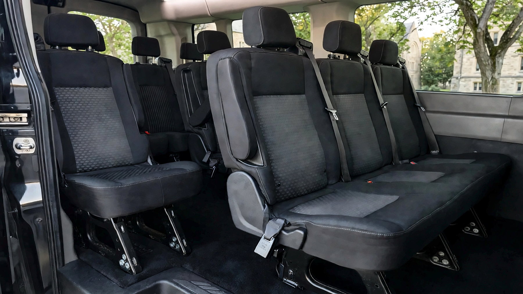 Interior of the Ford Transit 250 with black cloth passenger seating and seat belts